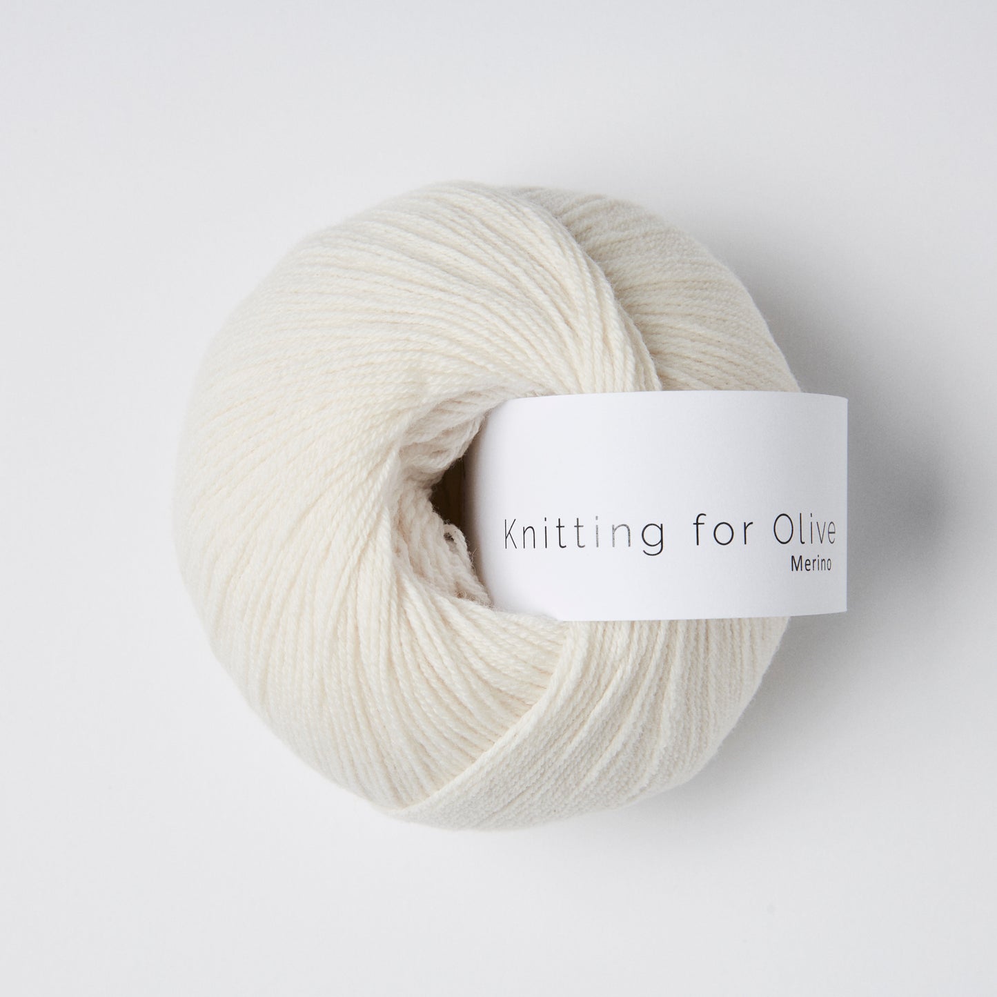 Ball of cloud colored merino fingering yarn with a white Knitting for Olive brand label