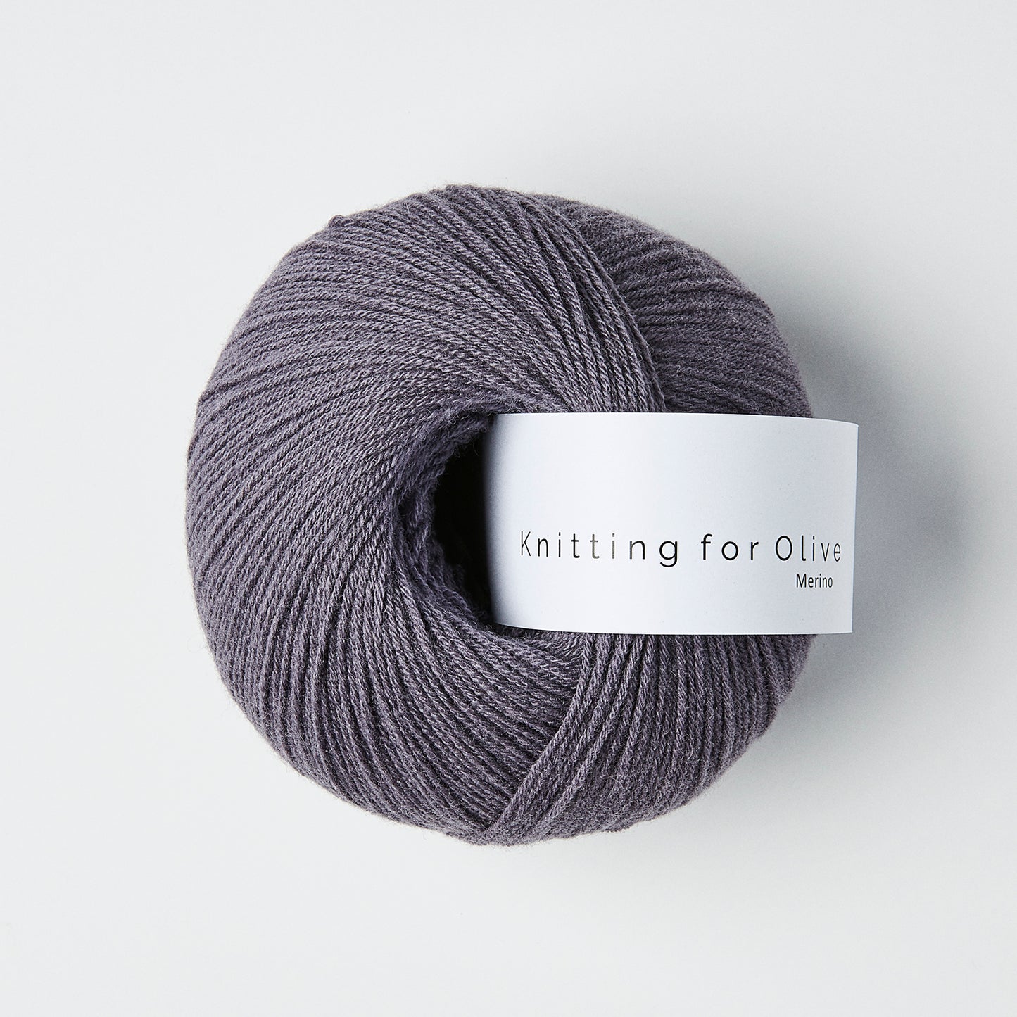 Ball of dusty violette colored merino fingering yarn with a white Knitting for Olive brand label