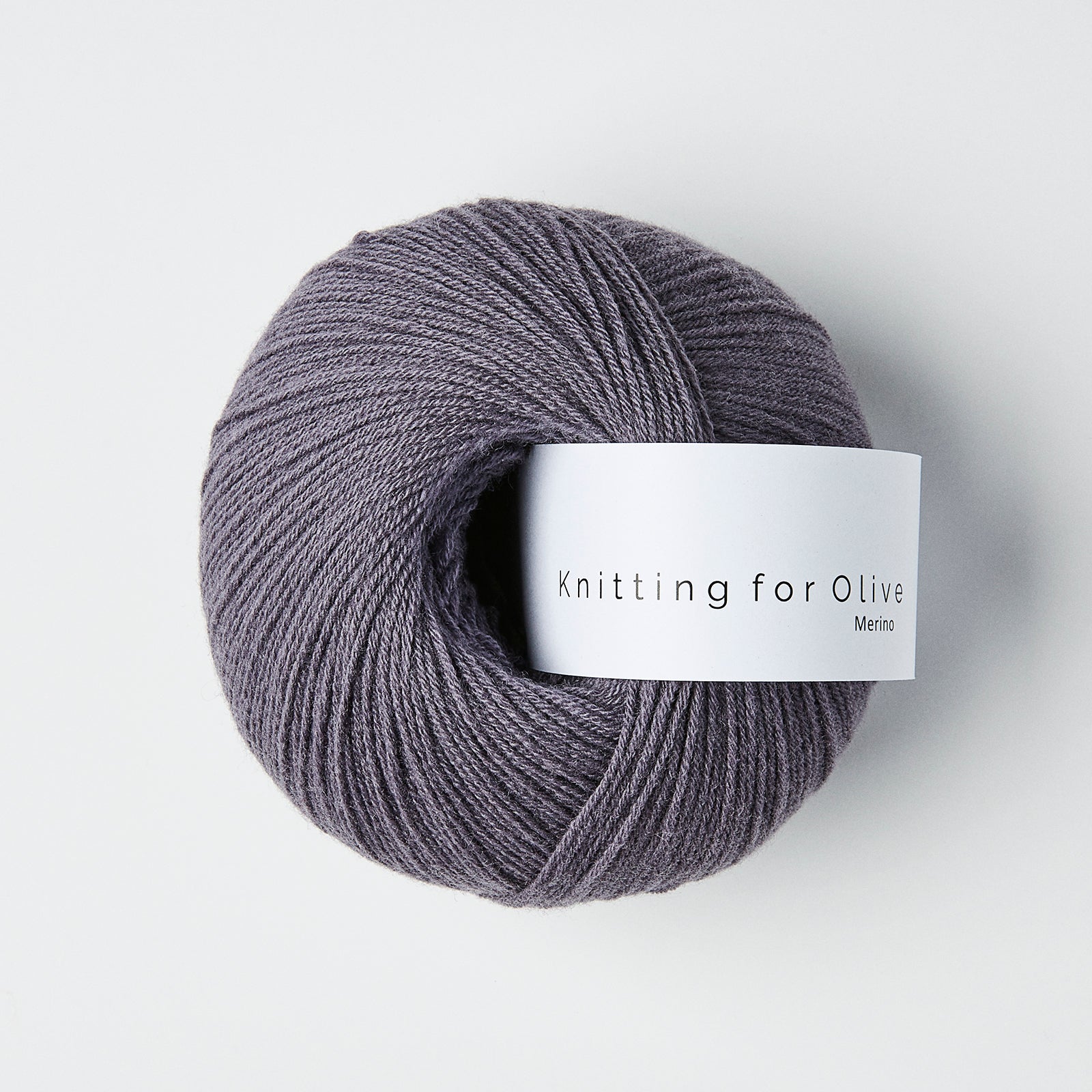 Ball of dusty violette colored merino fingering yarn with a white Knitting for Olive brand label