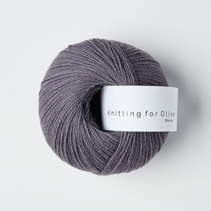 Ball of dusty violette colored merino fingering yarn with a white Knitting for Olive brand label