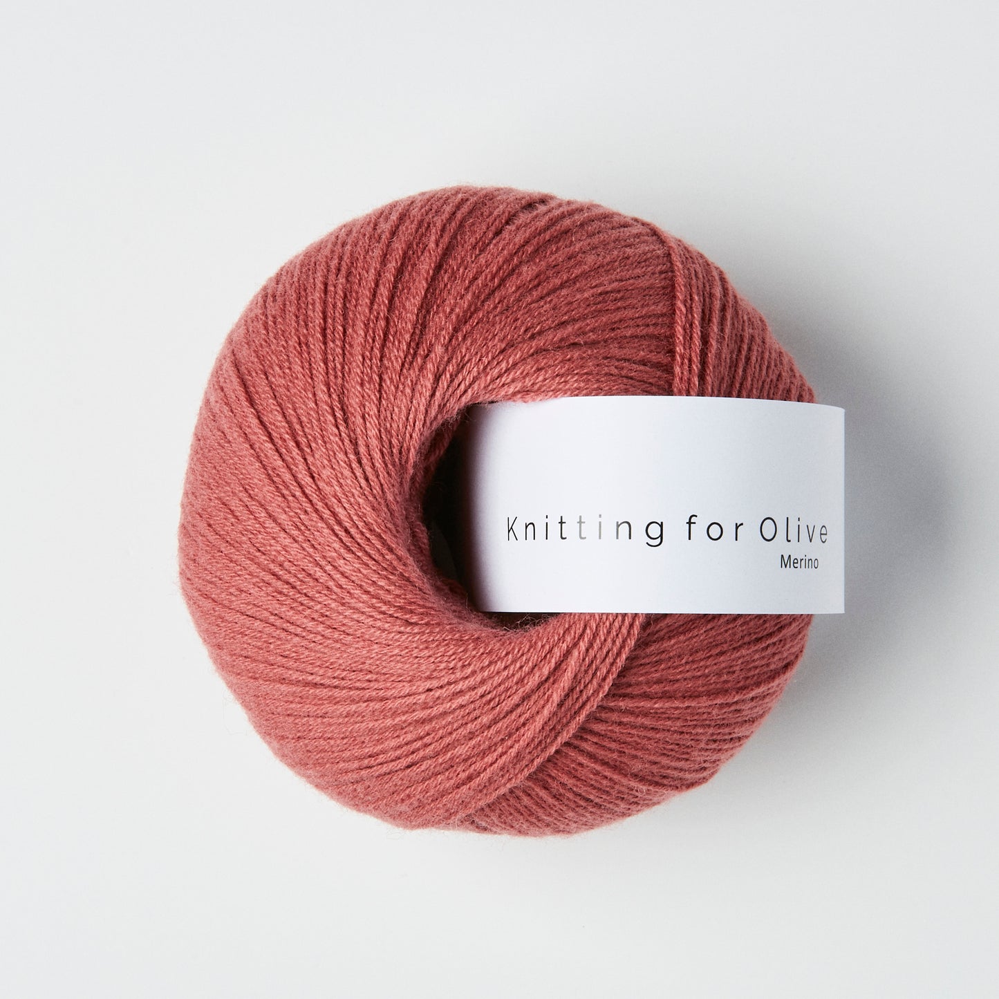 Ball of wild berry colored merino fingering yarn with a white Knitting for Olive brand label